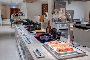 Una barra de buffet con diversos alimentos y utensilios.