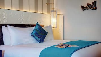 A hotel room with a bed, pillows, a magazine, a wall with decorative panels, and a wall-mounted light fixture.