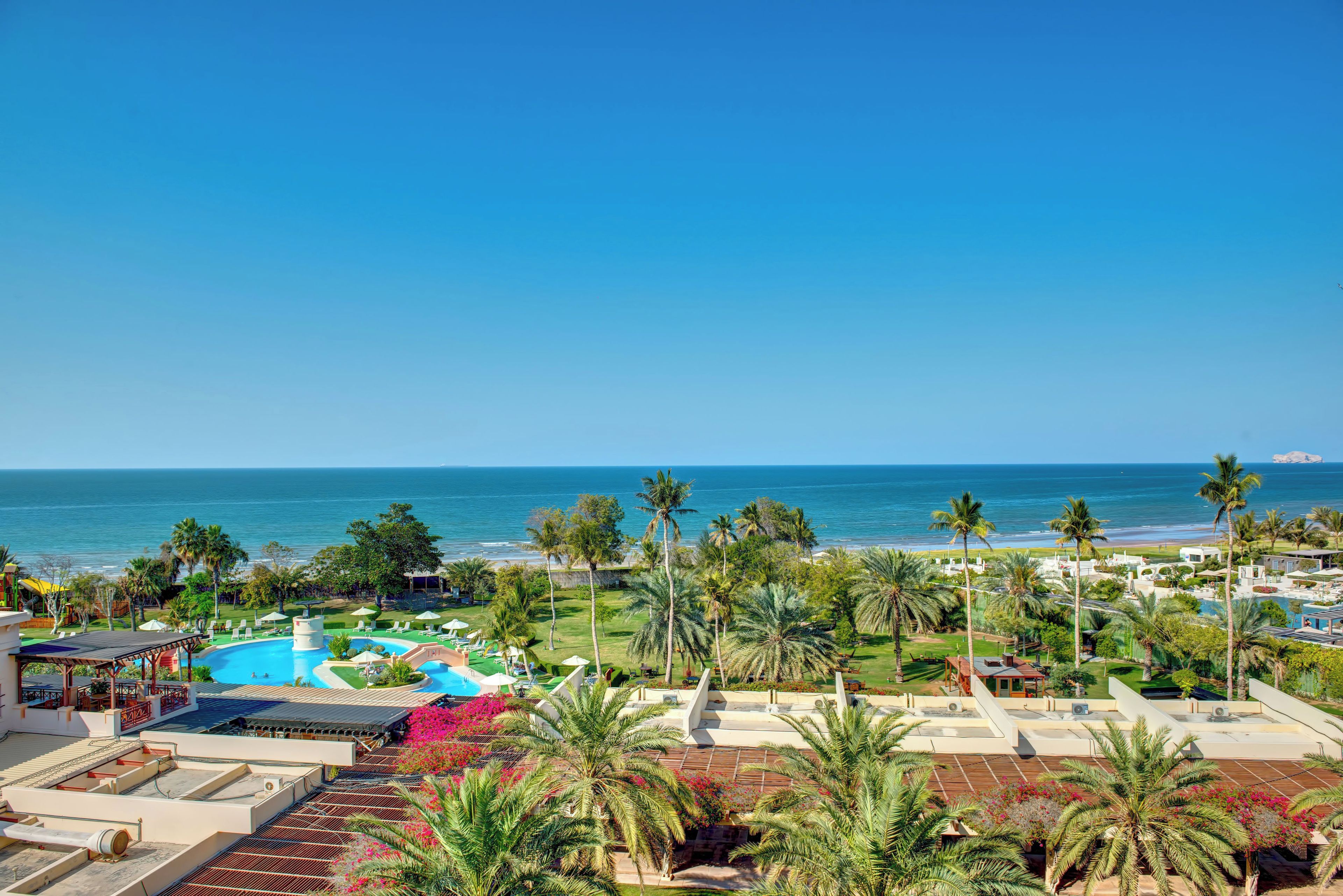 Un resort con piscina, palmeras y vista al océano.