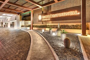 A hotel entrance with a sign reading "INTERCONTINENTAL MUSCAT" and a paved walkway leading to the lobby.