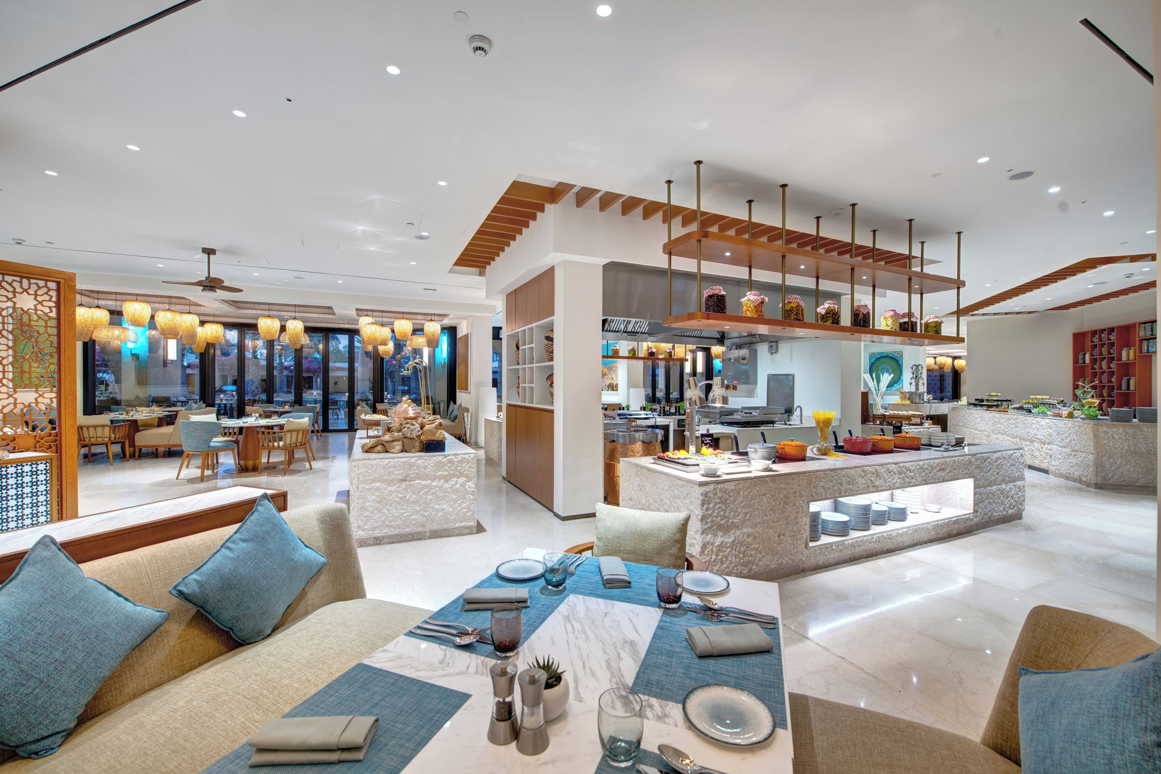 Un hall d’hôtel moderne comprenant un espace repas, une cuisine et un comptoir d’accueil.