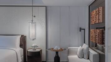 Een moderne hotelkamer met een bed, een ronde tafel met dienblad, een bank en een decoratief wandpaneel.