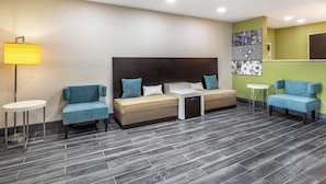 A modern hotel room with a sofa bed, a small table, and a lamp.