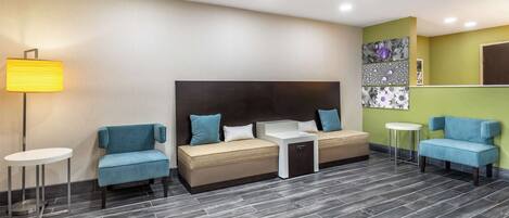 A modern hotel room with a sofa bed, a small table, and a lamp.