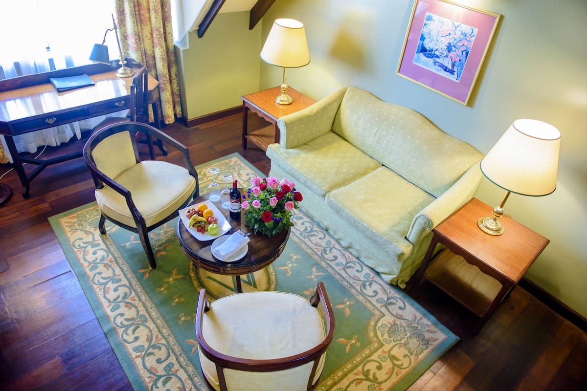 Un salon chaleureux avec un canapé, deux fauteuils, une petite table sur laquelle est posé un vase de fleurs et deux lampes.