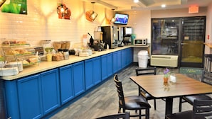 Una barra de desayuno con encimera azul, un televisor y un refrigerador.
