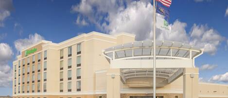 A hotel with a large entrance, a flagpole with the American flag, and a Holiday Inn sign.