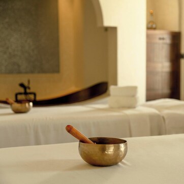 A hotel room with two beds, a wooden bowl, and neatly folded towels.