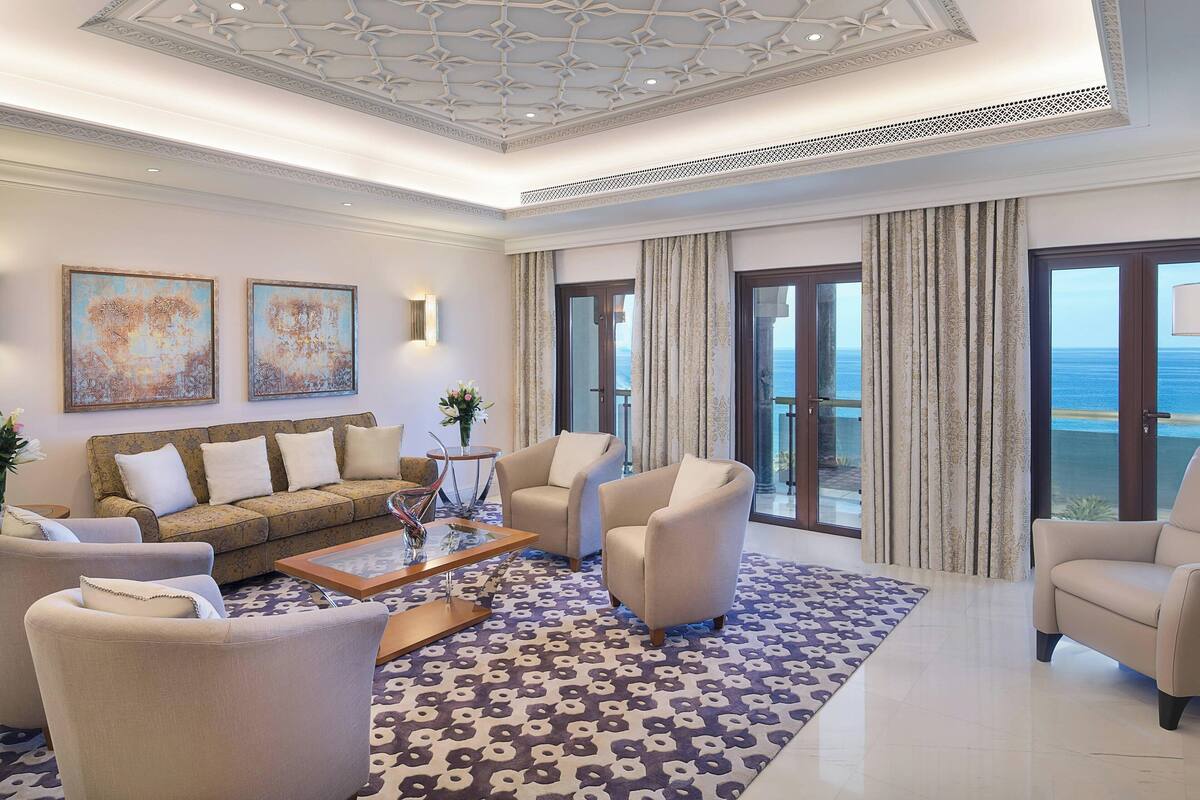 A spacious living room with a sofa, armchairs, a coffee table, and a patterned rug.