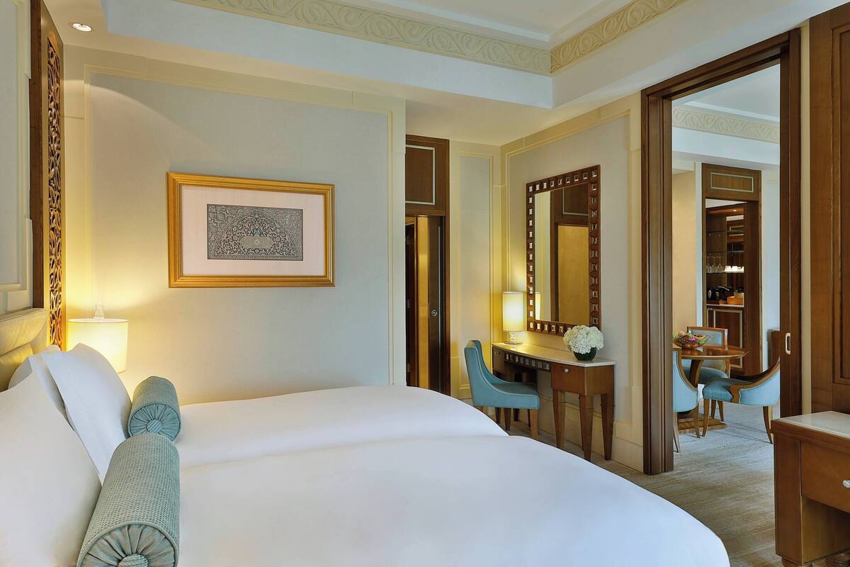 A hotel room with a large bed, a desk with a chair, a mirror, and a framed picture on the wall.