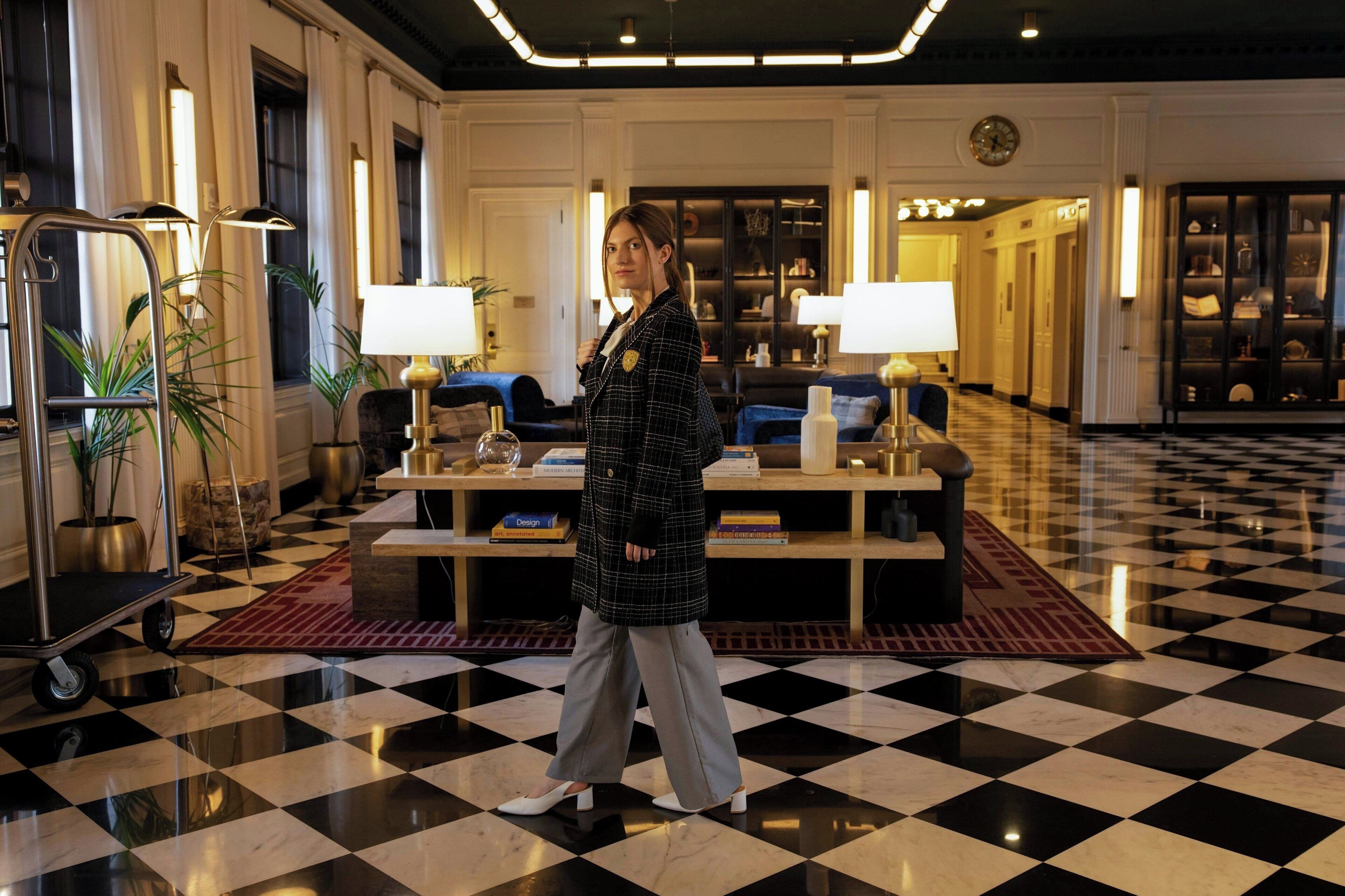 A lobby with a checkered floor, a reception desk, and a seating area with lamps.