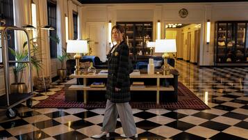 A lobby with a checkered floor, a reception desk, and a seating area with lamps.