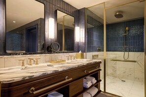 A bathroom with a marble vanity, a large mirror, and a glass-enclosed shower.
