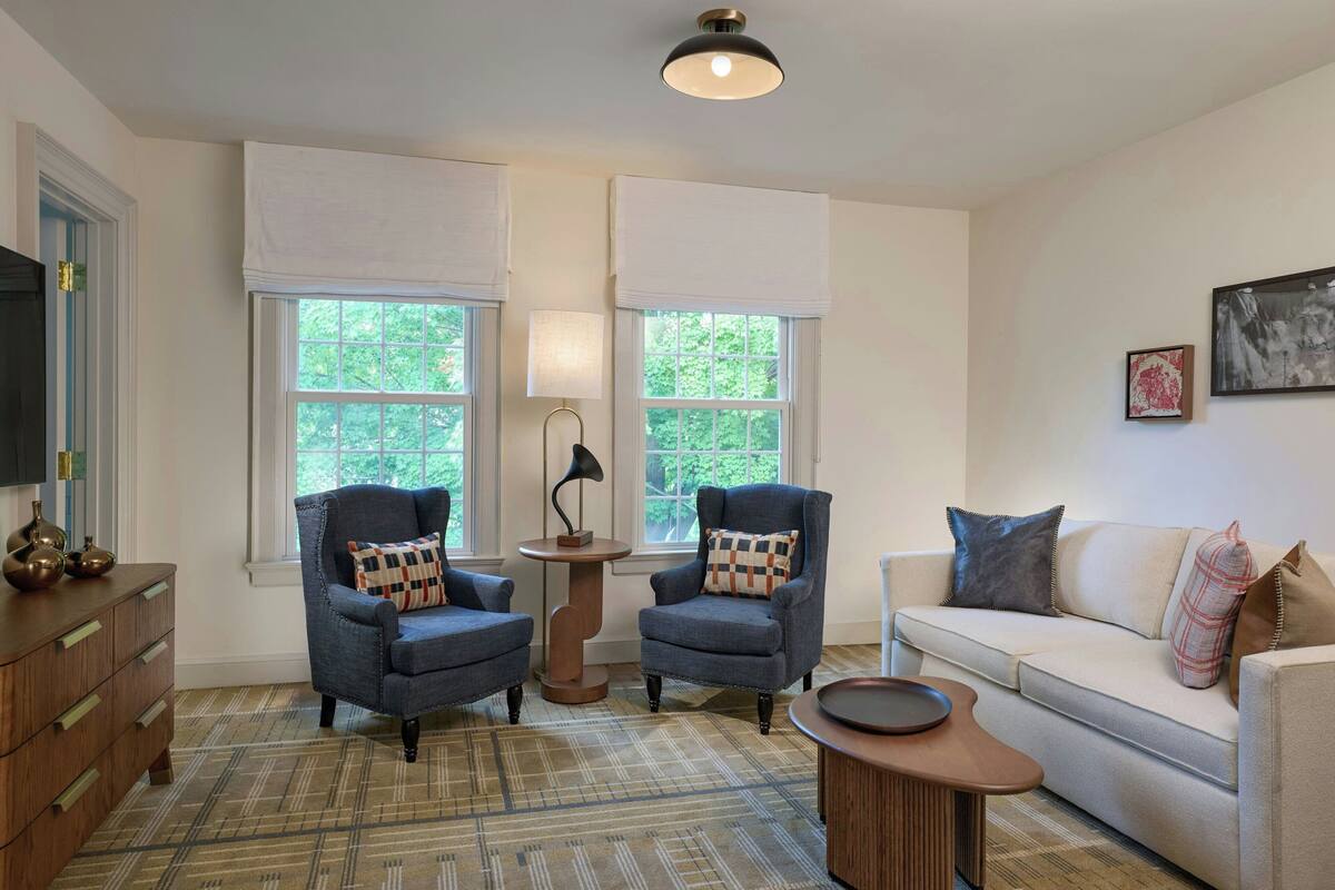 A living room with two armchairs, a sofa, a coffee table, and a TV on a wooden cabinet.