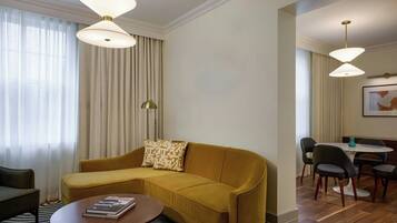 A modern living room with a mustard sofa, a round coffee table, and a dining area with a table and chairs.