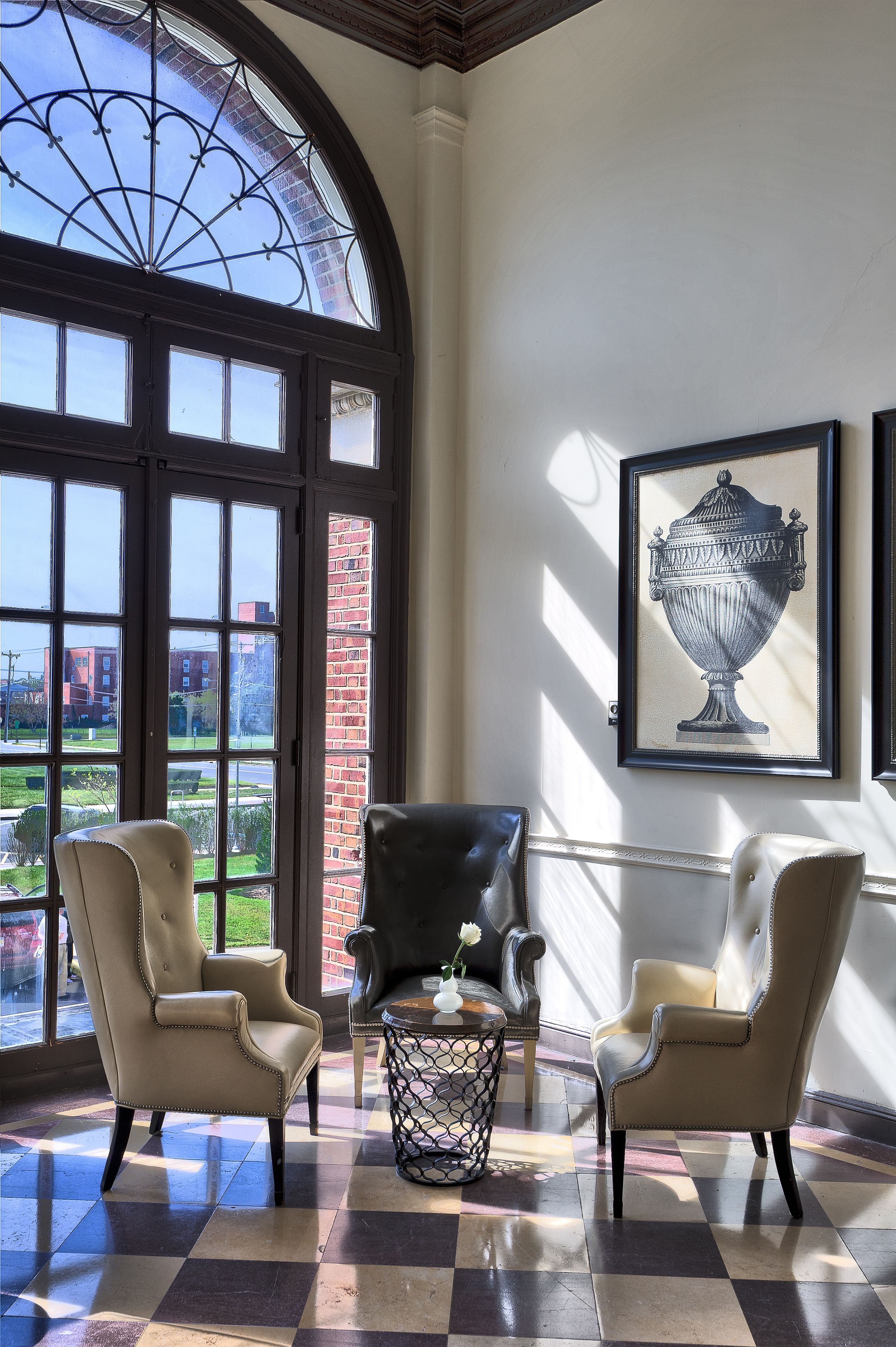 A room with two leather armchairs, a patterned floor, a large window with a view, and a framed artwork on the wall.