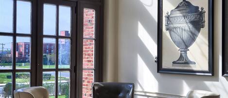 A room with two leather armchairs, a patterned floor, a large window with a view, and a framed artwork on the wall.
