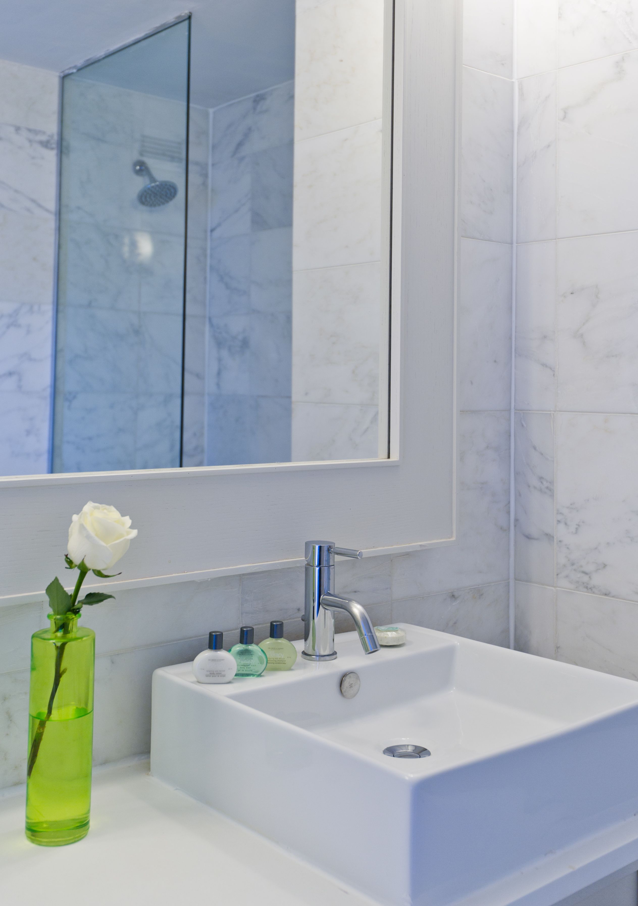 A bathroom with a white sink, a mirror, and a glass shower enclosure.
