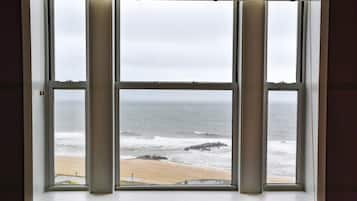A window with a view of the ocean and a sandy beach.