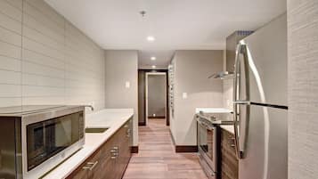 Una cocina moderna con electrodomésticos de acero inoxidable, armarios de madera y salpicadero de azulejos.