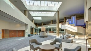 A spacious lobby with a high ceiling, a central seating area, and a staircase leading to upper floors. - Marriott Tulsa Hotel Southern Hills (Tulsa)