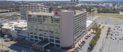 A multi-story hotel with a prominent 'Marriott' sign, a parking lot, and a view of the surrounding cityscape.
