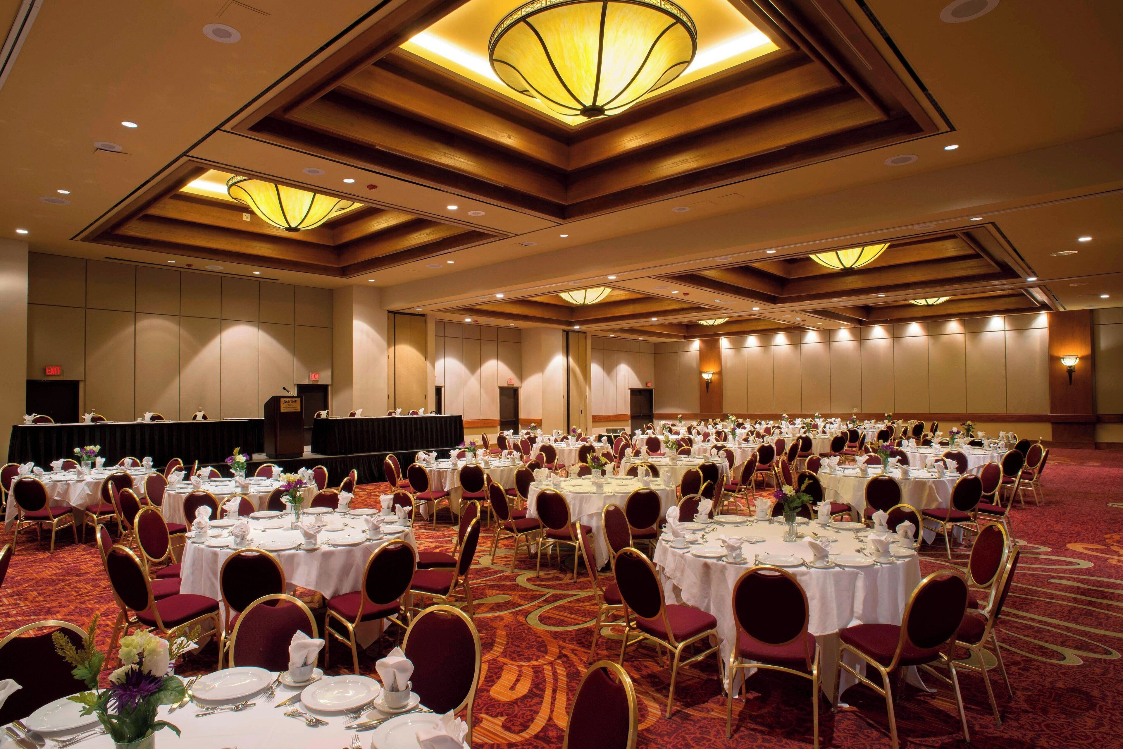A banquet hall with round tables set for dining, equipped with chairs and table settings.