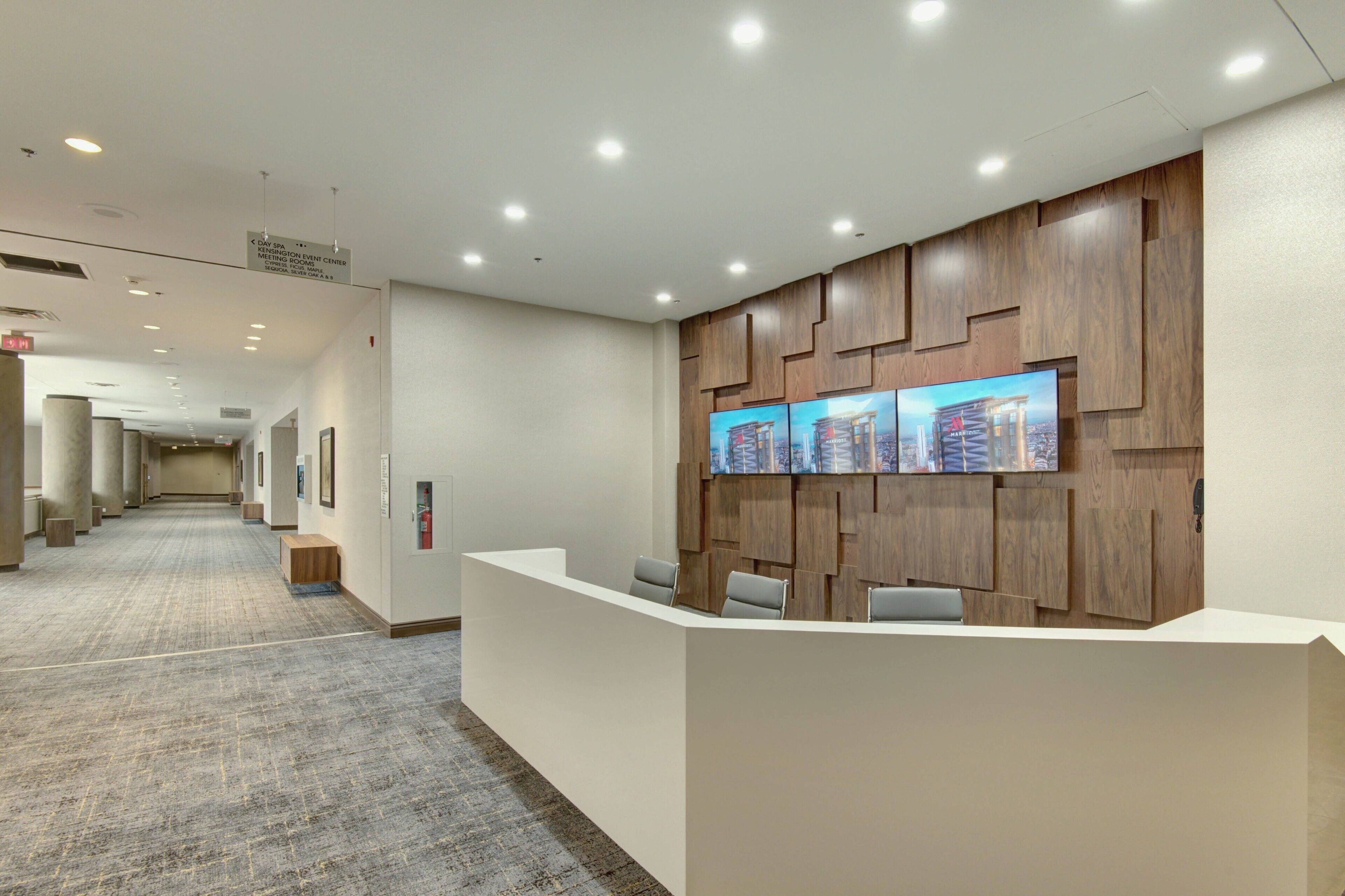 Et moderne receptionområde med en lang gang, en reception og en vægmonteret skærm.