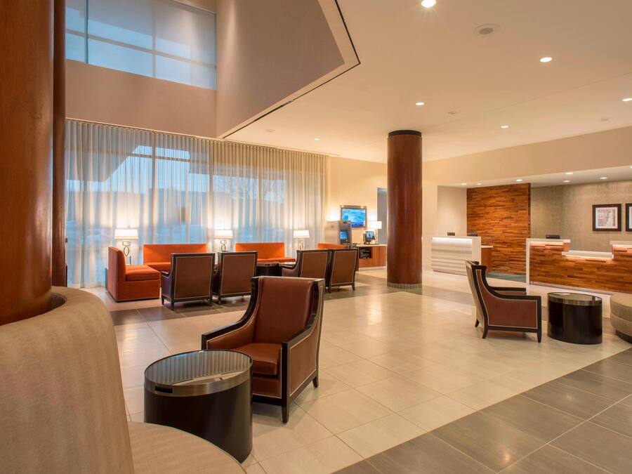 Un moderno vestíbulo de hotel con mostrador de recepción, zona de estar y amplias ventanas.