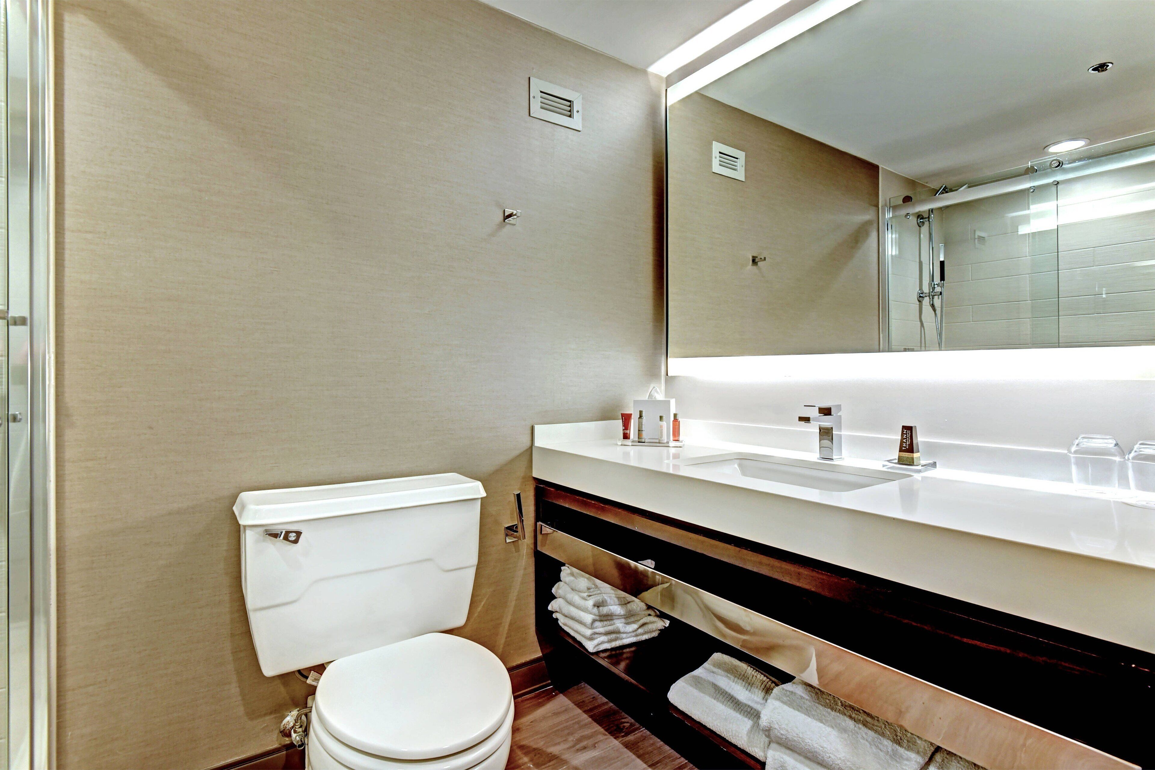 Un baño moderno con inodoro, lavabo y espejo.