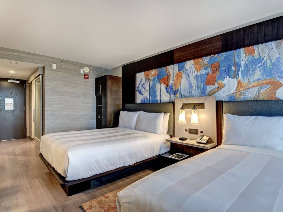 A hotel room with two beds, a large abstract painting on the wall, and a modern design.