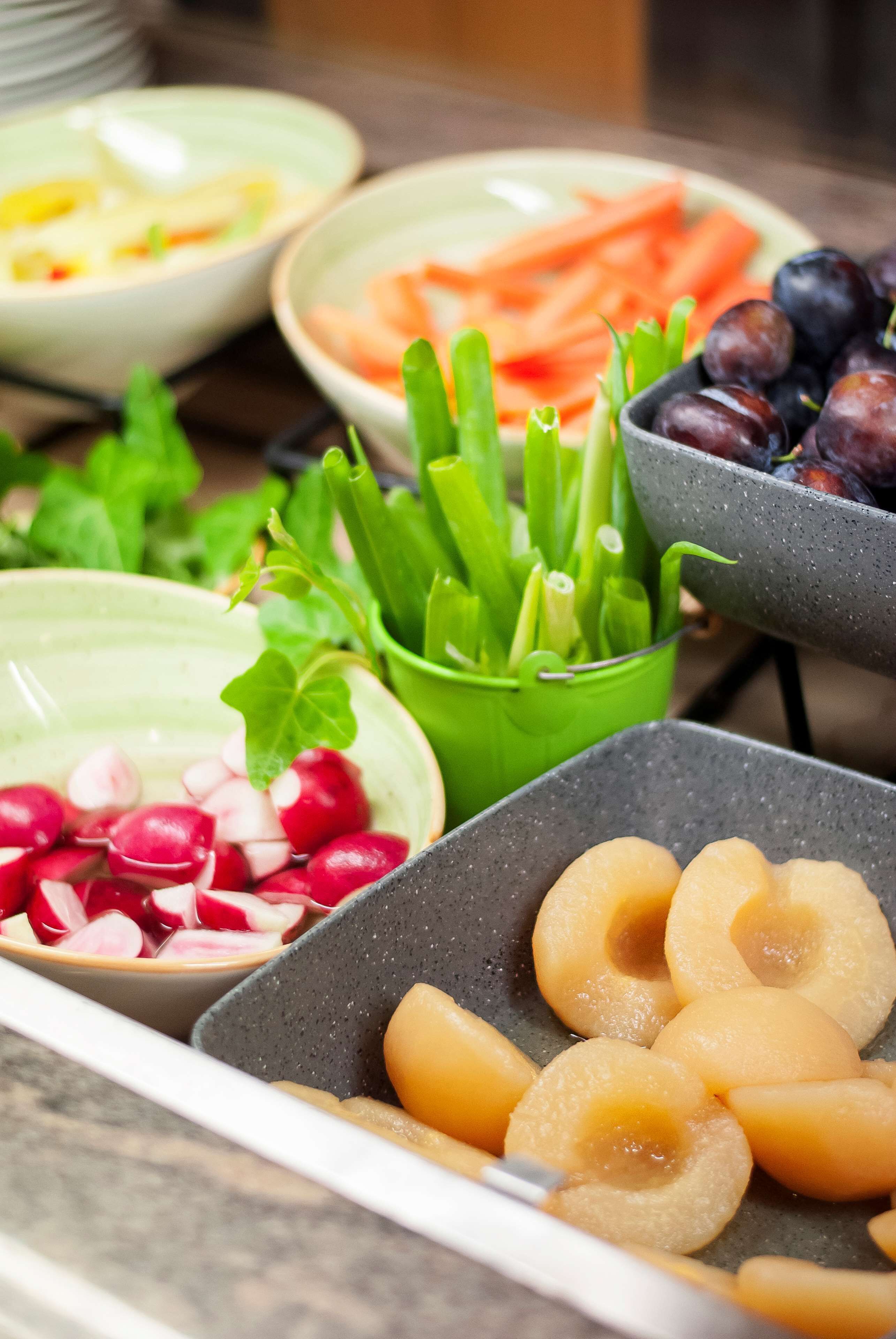 Diversos alimentos como rábanos, zanahorias y uvas dispuestos sobre una mesa.