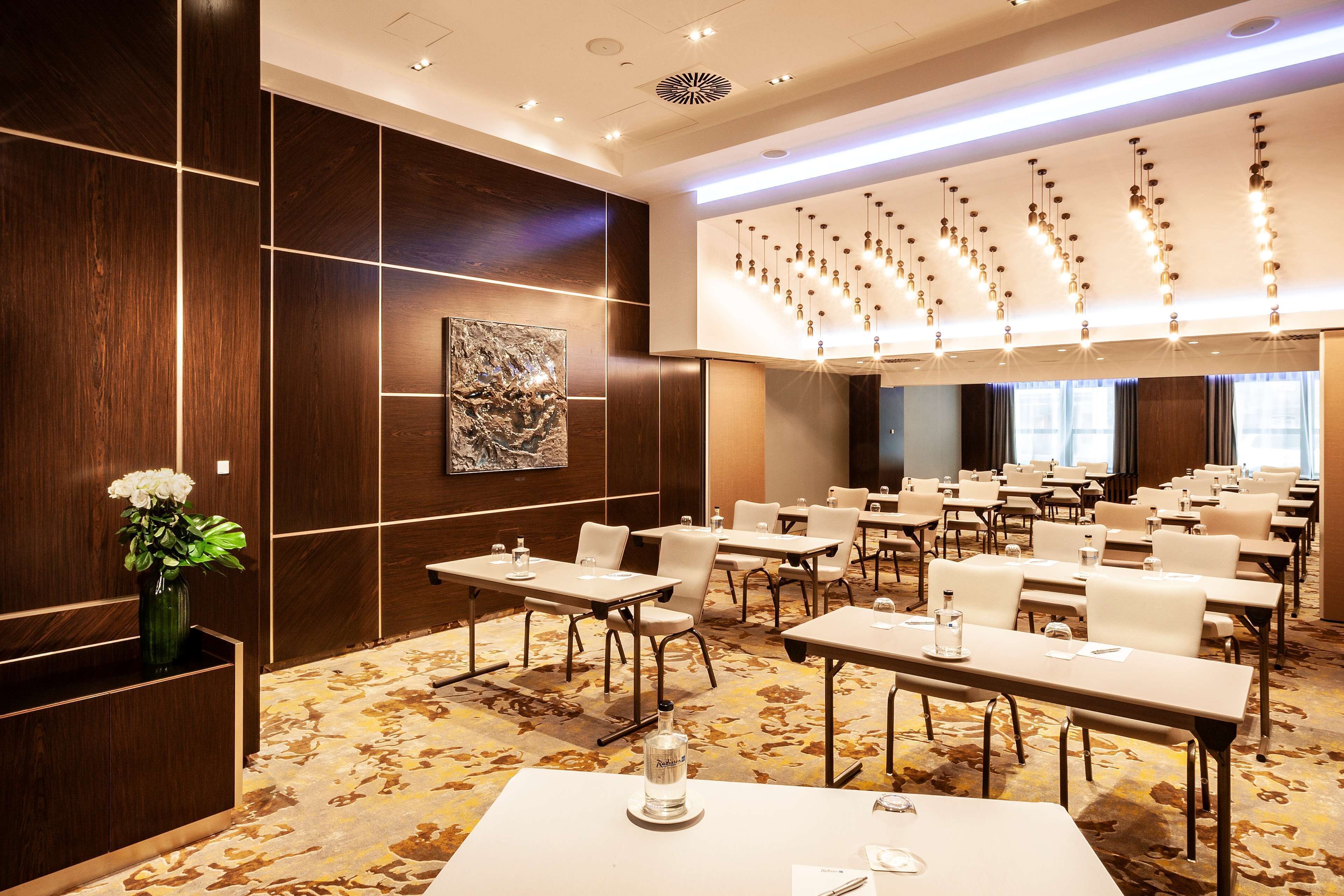 A conference room with tables and chairs, a vase with flowers, and a modern chandelier.