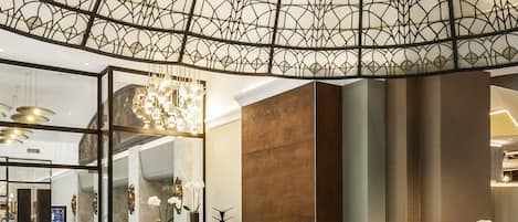 A modern interior with a geometric ceiling design, a central fireplace, and a seating area with tables and chairs.