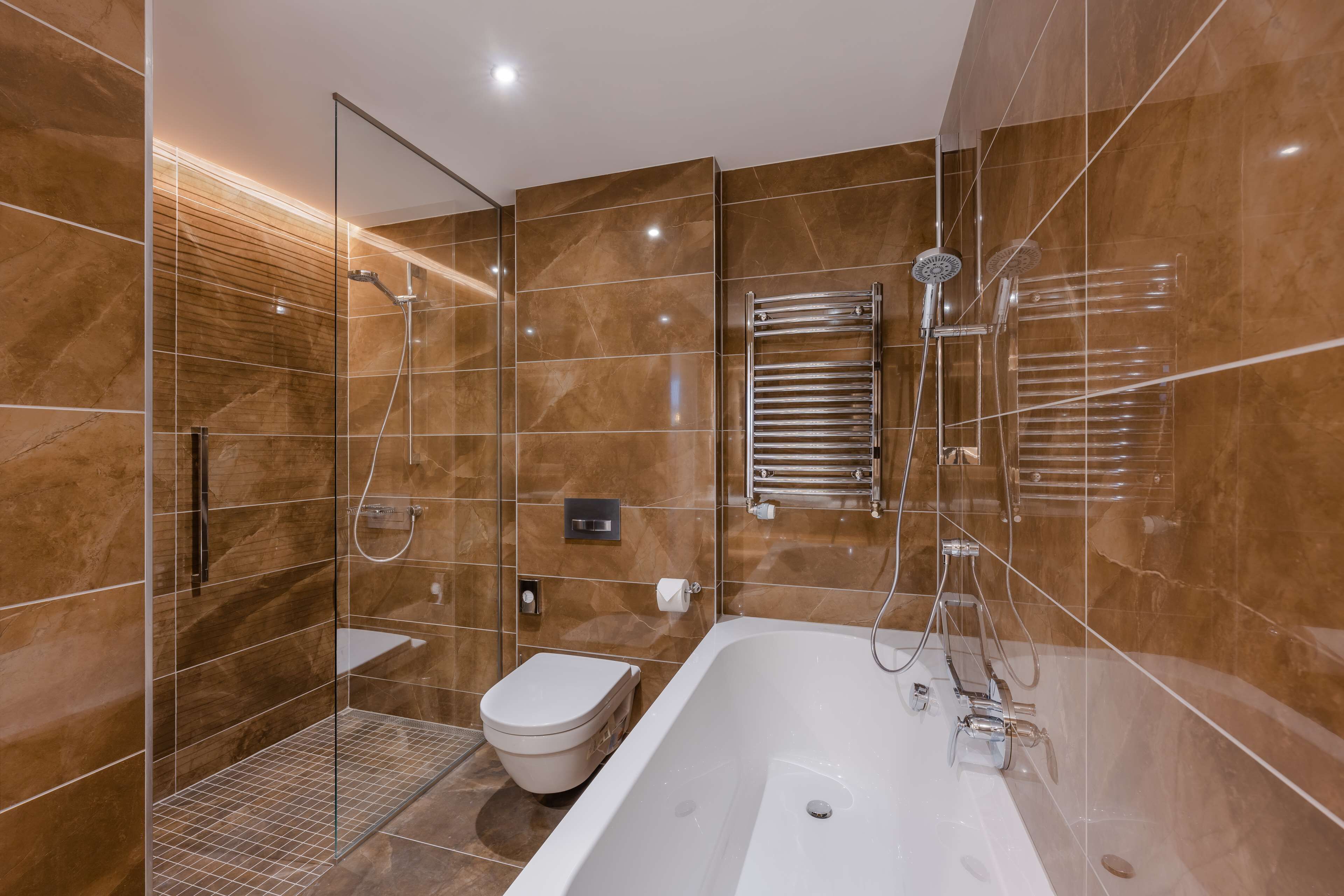 Un baño moderno con ducha envuelta en vidrio, un inodoro independiente y una bañera separada.