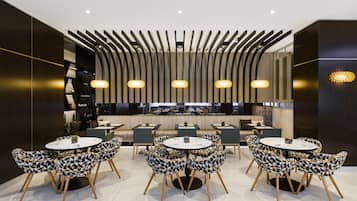A modern restaurant with round tables and patterned chairs, featuring a unique ceiling design and pendant lighting.
