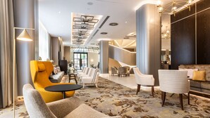 A modern lobby with a central seating area, a staircase, and a large window. - Radisson Blu Beke Hotel, Budapest (Budapest)