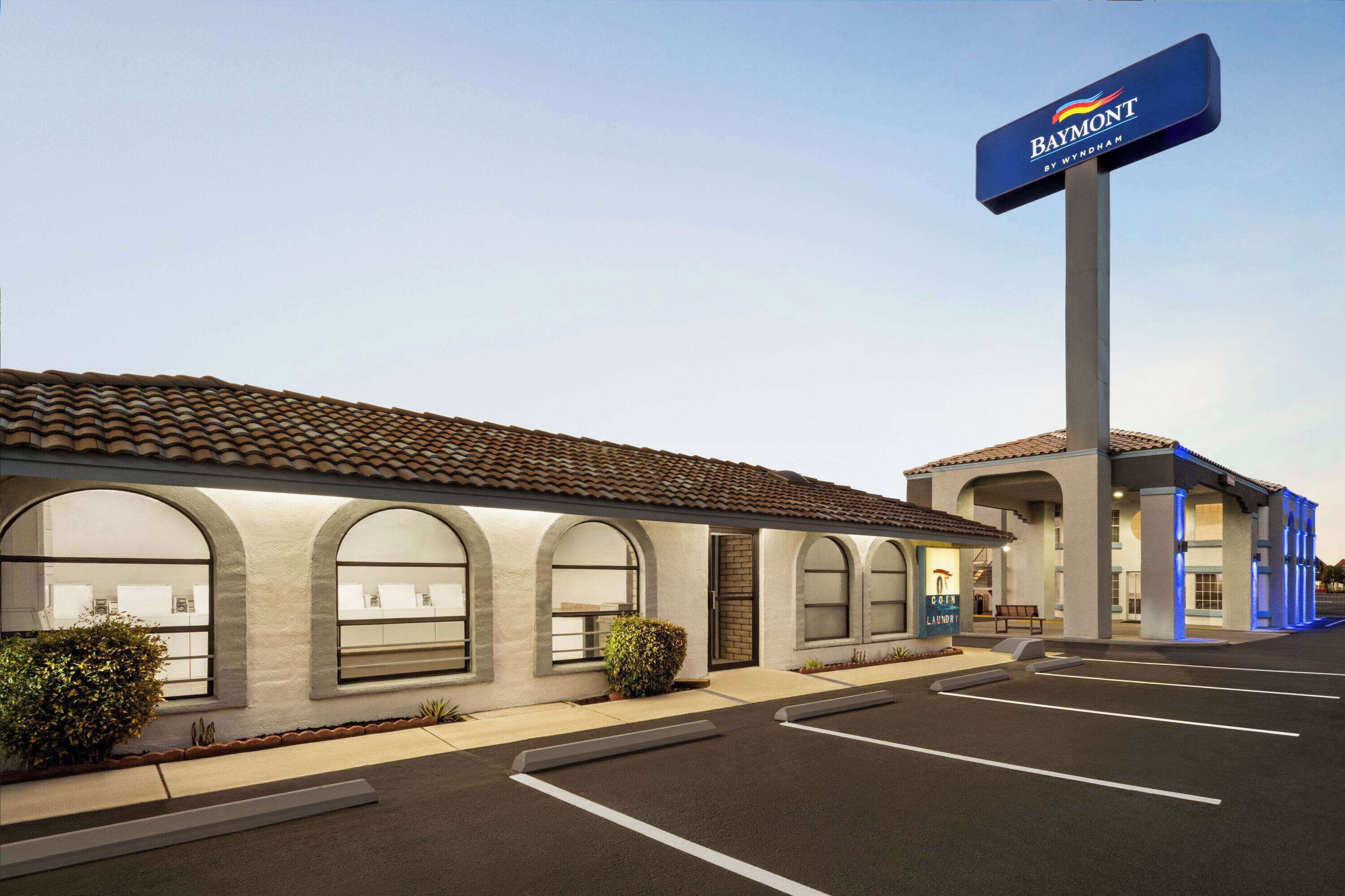 A Baymont by Wyndham hotel with a tiled roof, arched windows, and a parking lot.