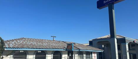 A Baymont by Wyndham hotel with a blue and white exterior, a sign indicating coin-operated laundry, and a cable TV sign.