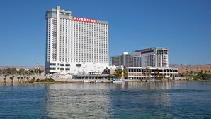 A large hotel with a prominent Riverside Casino sign, situated by a body of water with a boat docked nearby. - Baymont by Wyndham Kingman (Kingman)