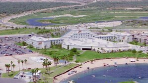 A coastal resort with a central building surrounded by a parking lot, a beach, and a marina. - Baymont by Wyndham Kingman (Kingman)