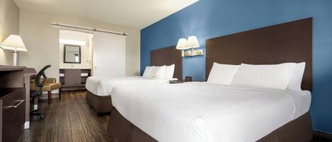 A hotel room with two beds, a desk, and a chair.