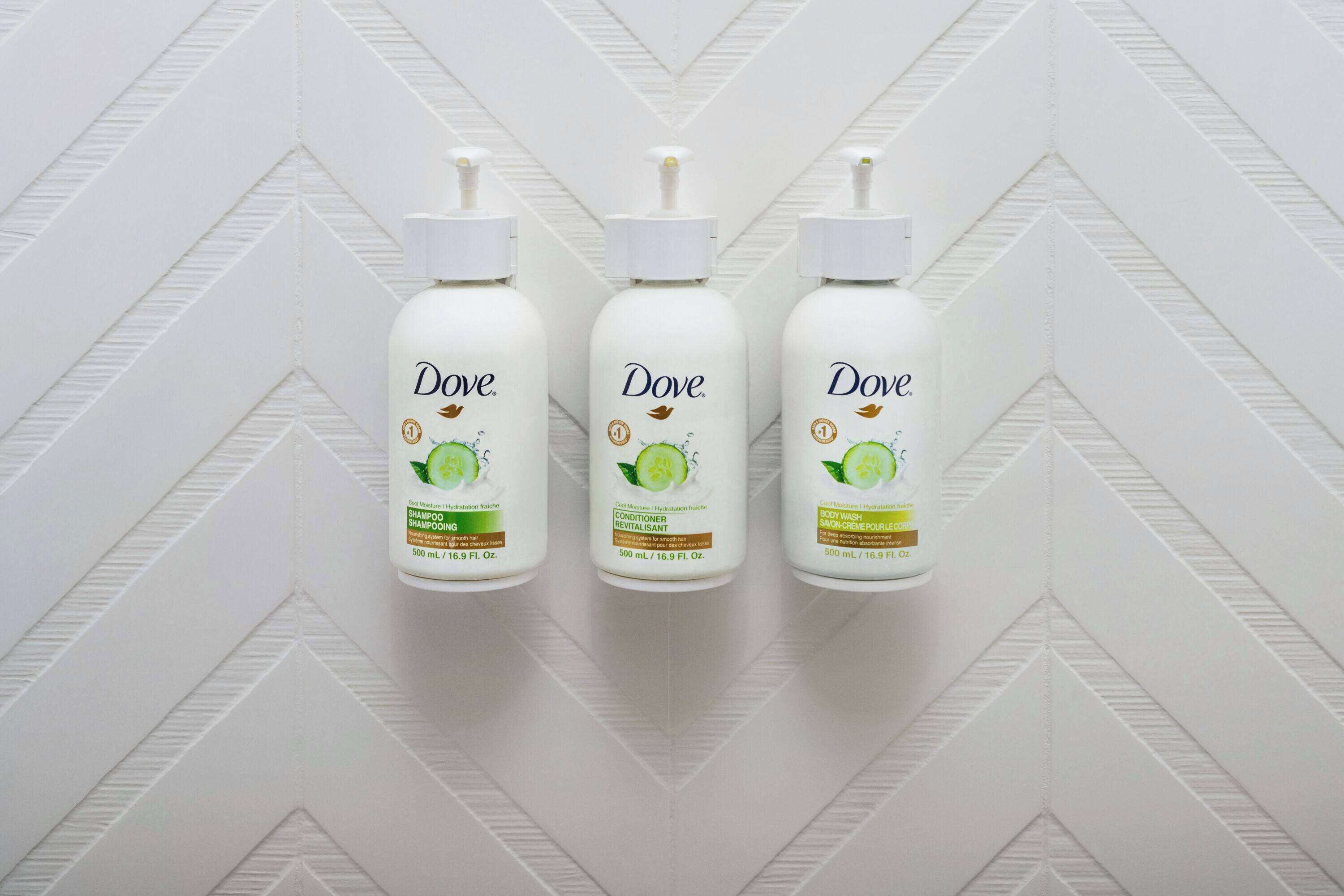 Three Dove personal care products against a white chevron-patterned wall.