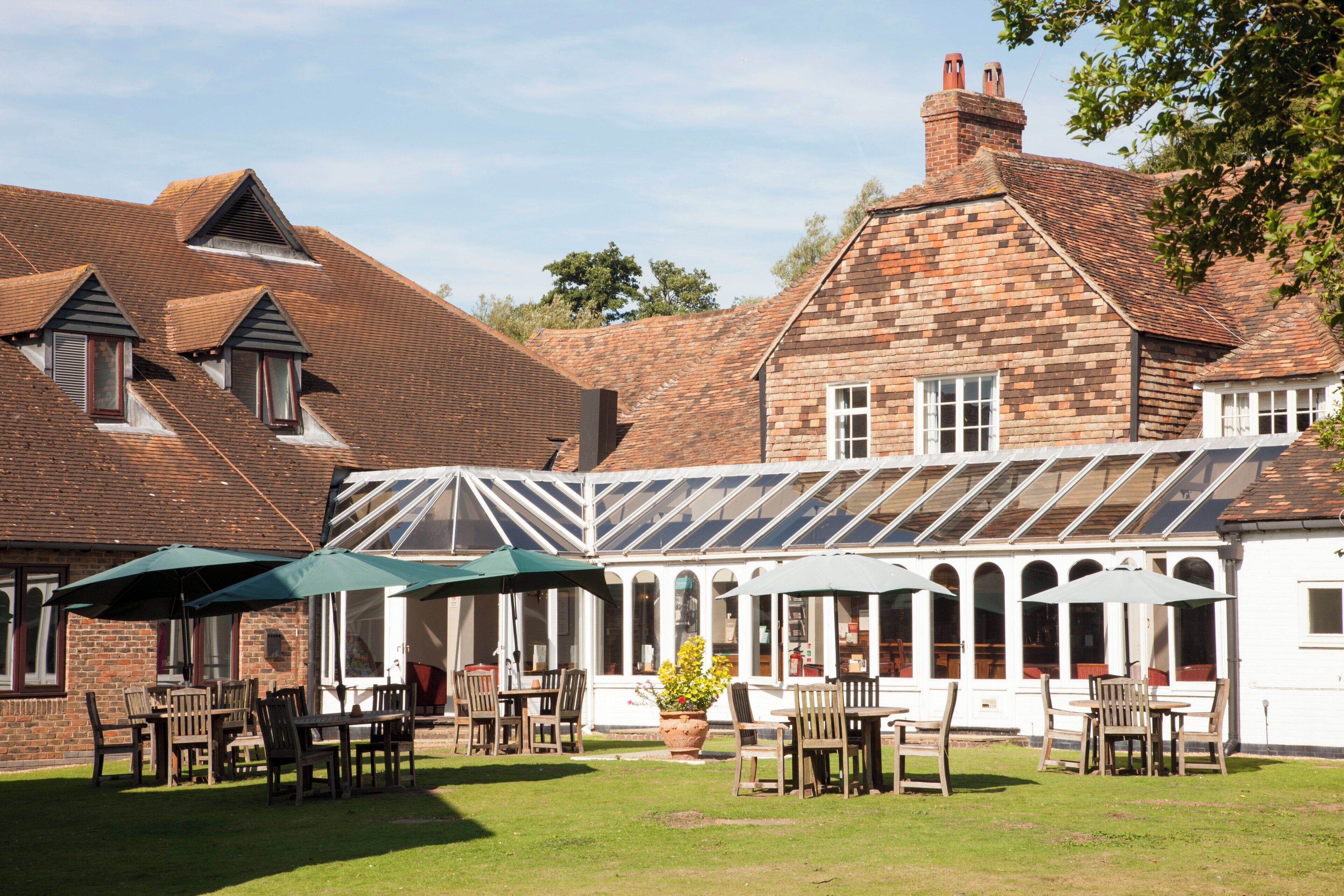 A traditional building with a conservatory, outdoor seating, and a brick facade.