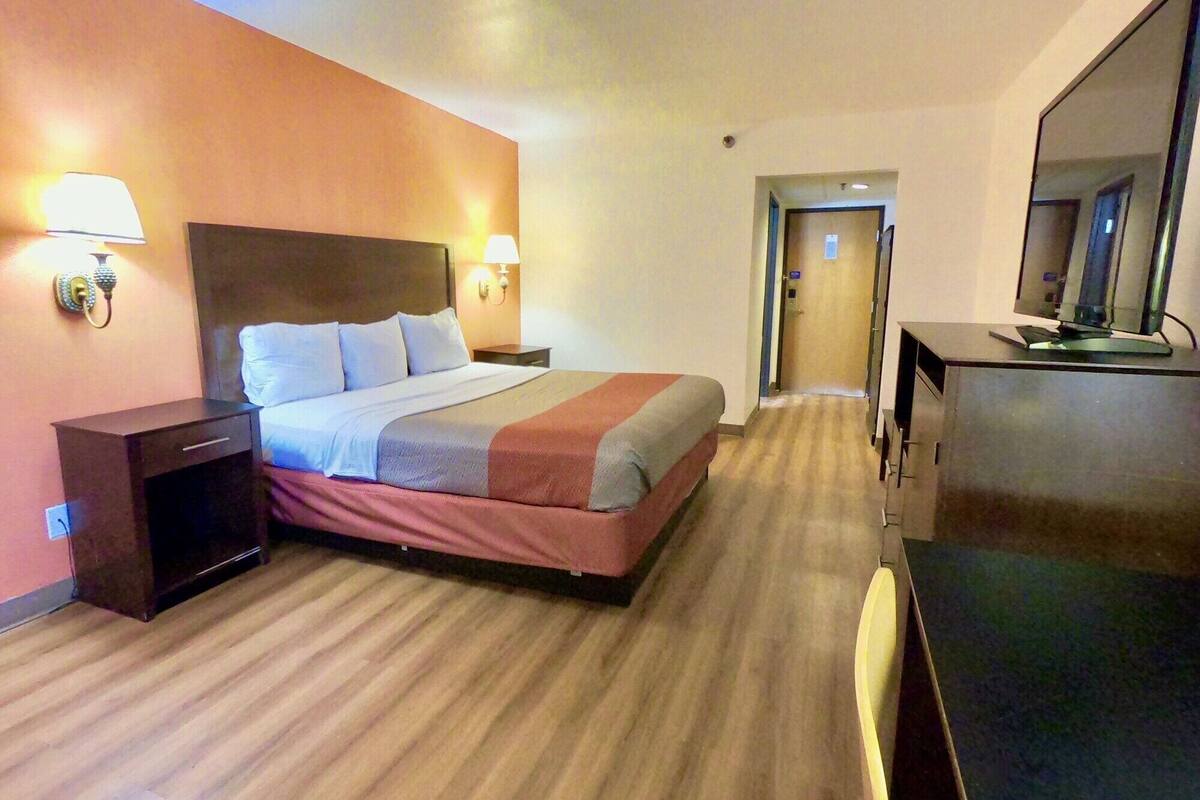 Ein Hotelzimmer mit Bett, Nachttischen, einem Schreibtisch und einem Spiegel.