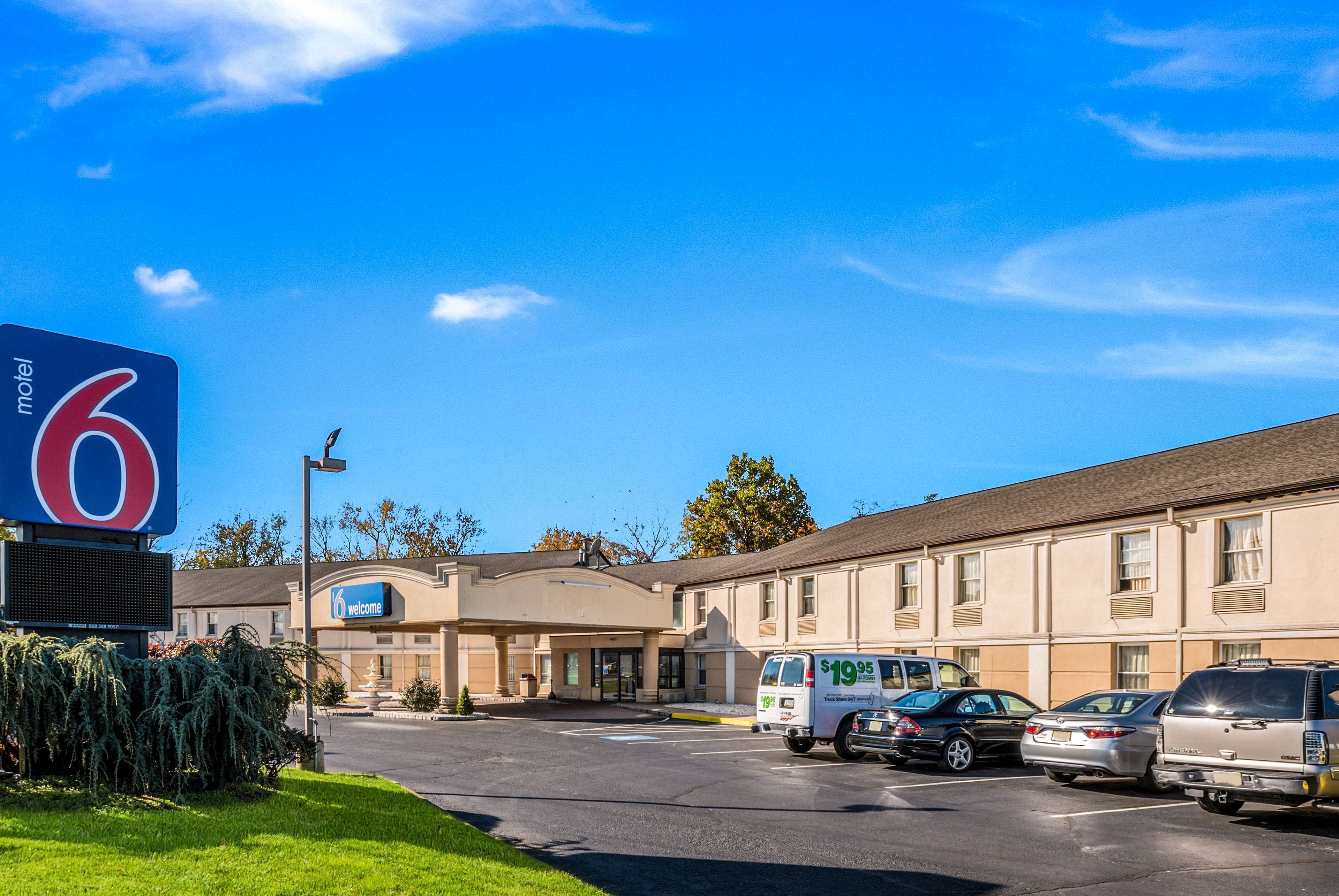 Un motel avec une grande enseigne, un parking et plusieurs véhicules stationnés.