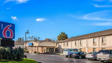 Un motel avec une grande enseigne, un parking et plusieurs véhicules stationnés.