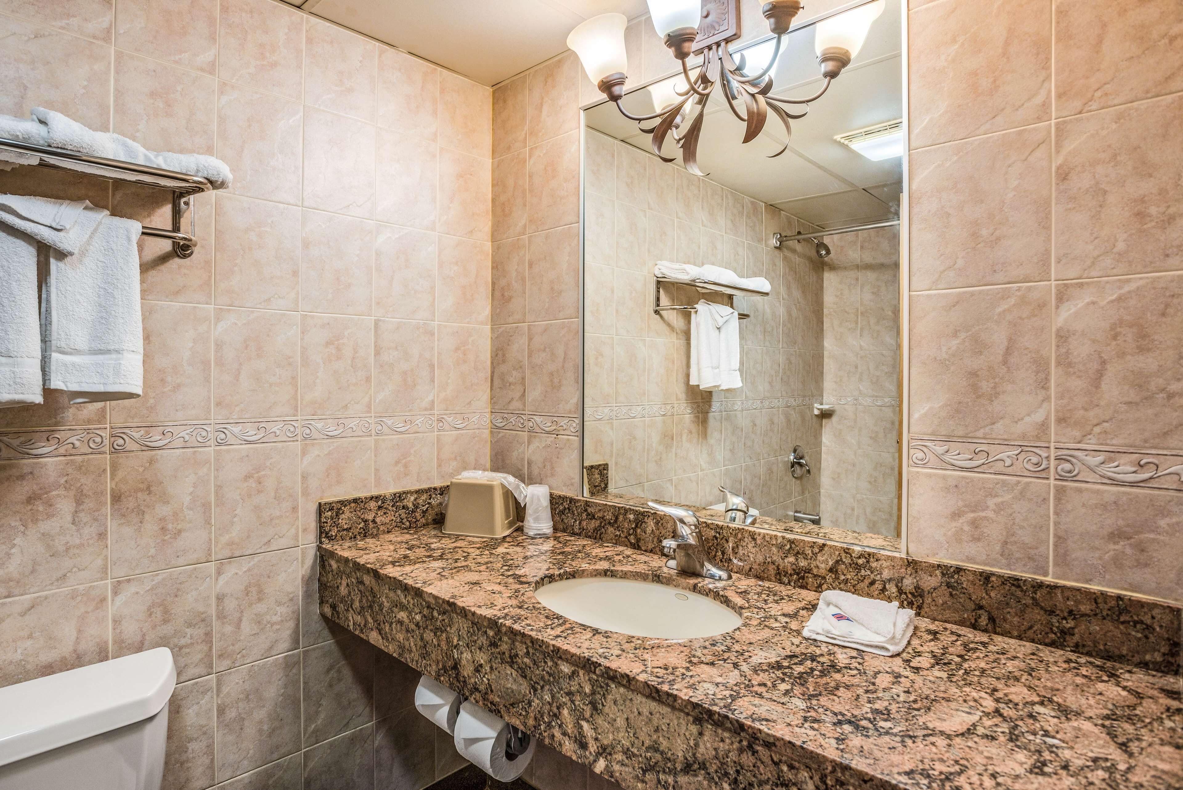A bathroom with a marble sink, a towel rack, a mirror, and a shower area.