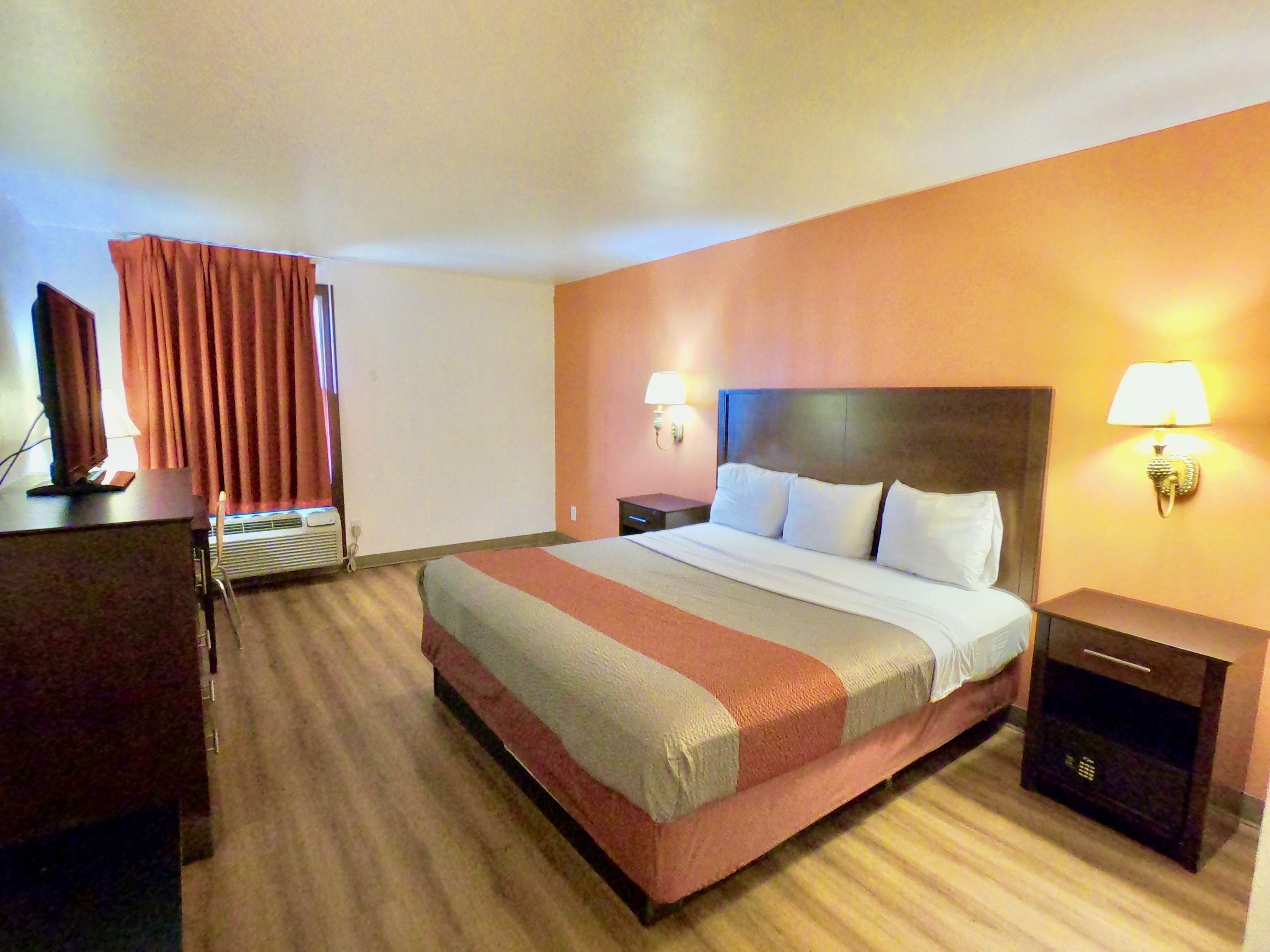 Habitación de hotel con una cama grande, un escritorio, una lámpara y una mesita de noche.