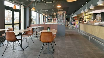 Un café moderne doté d’un bar, de tables et de chaises, et d’un éclairage suspendu.